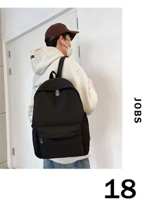 Detail of black nylon backpack featuring large front pocket and silver metal zippers