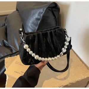 Detail of black pleated cloud bag with large pearl strap and silver heart chain charm