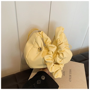 Detail of soft yellow pleated dumpling bag with flexible ruched handle and metal zipper
