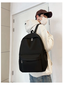 Rear view of a minimalist black nylon backpack with a silver U-shaped metal zipper pull