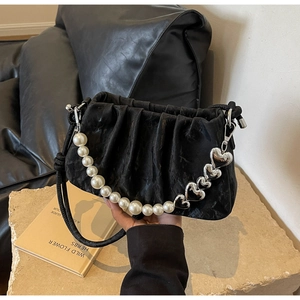 Detail of black pleated cloud bag featuring pearl and silver heart shoulder strap charms