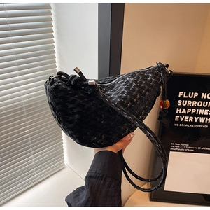 Detailed shot of a black woven crescent bag with decorative amber bead and knotted strap