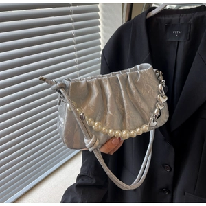 Close-up of silver pleated texture bag with pearl and heart metallic strap details