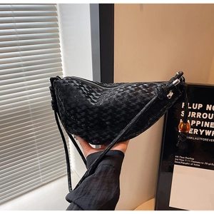 Close-up of black woven leather crescent bag with unique amber bead charm detail