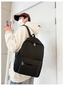Side view of student wearing a large black nylon school backpack with silver zippers