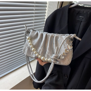 Detailed view of silver pleated hobo bag with large pearl chain and heart charm decor