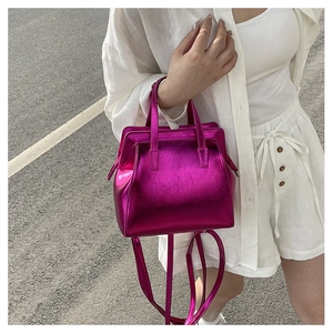 Detail of rose red metallic handbag with glossy finish and dual handles for women