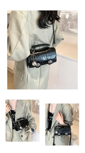 Détails du sac Boston noir avec texture craquelée, fermoir argenté et breloque ronde