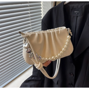 Detail of cream pleated cloud bag featuring pearl chain and silver heart charms