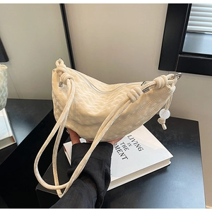 Detail of cream crossbody bag featuring wavy texture and unique knotted strap detail