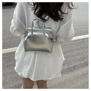 Close-up of metallic silver mini backpack with top handle and fashion logo lettering