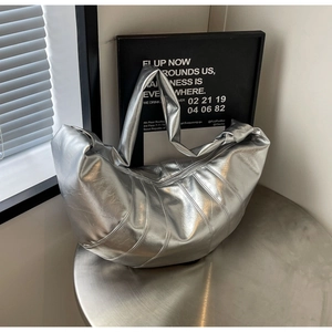 Close-up of silver dumpling bag with metallic texture and vertical stitching on metal stand