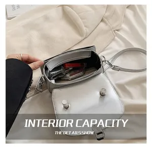 Detail showing the inner compartment of a silver crossbody bag with lipstick and perfume