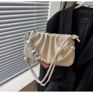 Detail of cream pleated cloud bag with pearl strap and silver heart chain accessories