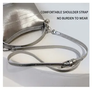 Silver bucket bag with brushed texture and metal ball charm on a minimalist white table