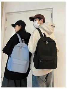 Rear view of models wearing light blue and black nylon backpacks in a casual urban setting