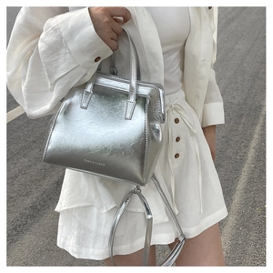 Outdoor shot of a silver metallic tote bag with fixed handle and detachable shoulder strap