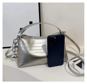 Silver textured bucket bag shown next to a smartphone to demonstrate product size