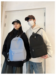 Front view of light blue and black nylon backpacks worn by male and female models