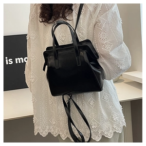 Chic black glossy trapezoid handbag shown on model with adjustable shoulder strap