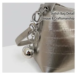 Detail of silver textured lunch bag with metallic sphere charm and metal ring closure
