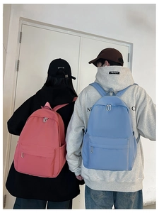 Detailed view of pink and light blue nylon backpacks with dual zippers and side pockets