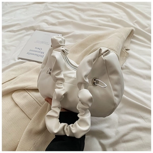 Detail of white pleated cloud bag with soft faux leather texture and ruffled strap