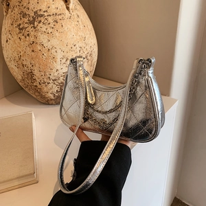 Silver quilted hobo bag with metallic chain and heart charm in a lifestyle setting
