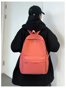 Detailed back view of a large coral orange nylon student backpack with side pockets