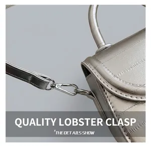 Detail of silver crossbody bag featuring high-quality metallic swivel hooks and strap