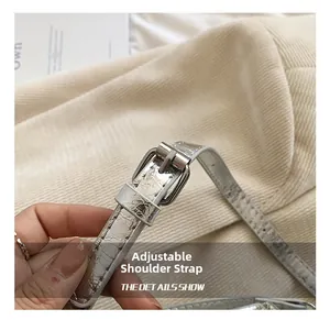 Gros plan d'une bandoulière réglable en cuir argenté craquelé avec boucle en métal