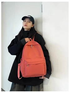 Detail of coral red nylon backpack with double zipper main compartment and front pocket