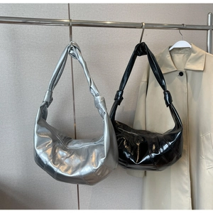Detail of glossy crescent bags with pleated stitching and knot handle details