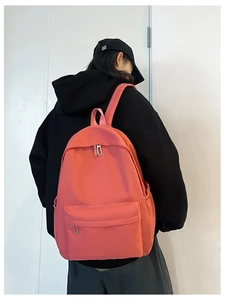 Rear view of coral pink nylon backpack on person featuring silver zippers and wide straps