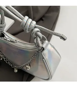 Detail of laser silver shoulder bag featuring metal chain with heart and pearl charms
