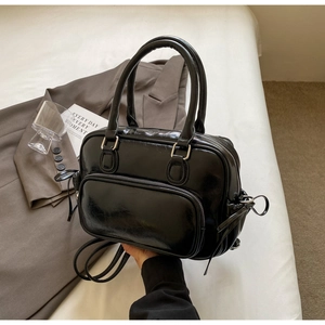 Detail of glossy black vintage handbag with front zipper pocket on a stylish background