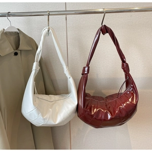 Detail of croissant bags with knotted shoulder straps and pleated stitching accents