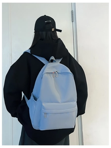 Rear view of a model wearing a light blue nylon backpack against a white background