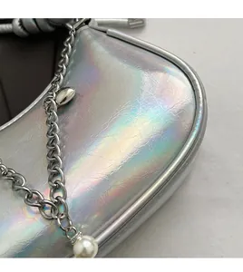 Detail of silver holographic chain bag featuring a large pearl charm and metallic finish