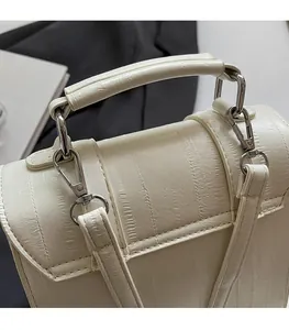 Detailed view of white embossed leather handbag with premium silver metal hardware