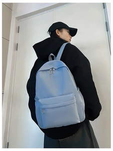 Side view of light blue nylon backpack on model showing large capacity and zipper detail