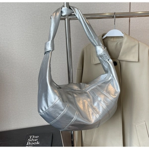 Detail showing the silver metallic bag with vertical stitching and knotted shoulder strap
