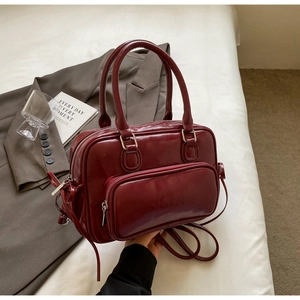 Detail of burgundy glossy oil wax leather handbag with silver hardware and front pocket