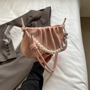 Pink pleated handbag with pearl accent and heart pendant in a chic lifestyle setting