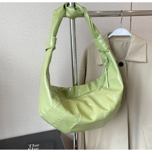 Close-up of light green patent leather croissant bag with stylish knotted strap detail