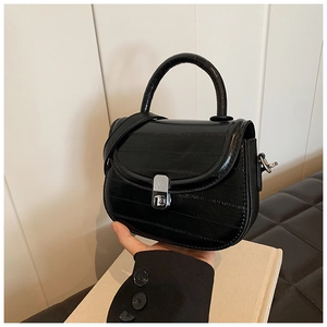 Detail of black semi-circular crossbody bag featuring silver turn-lock and textured leather