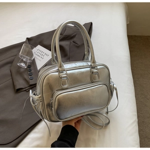 Detail of silver metallic Boston bag with bow accents and zip pocket on white bedding