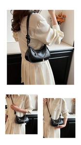 Detail of black glossy cracked leather hobo bag with pearl chain and knotted strap detail