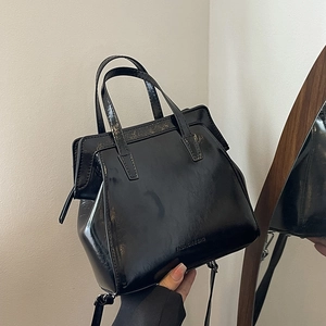 Minimalist black glossy leather handbag with dual handles and fashion engraving in 2024 style