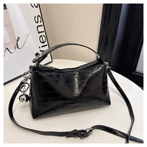 Close-up of black glossy bell bag with metallic texture, round handle and silver ball charm